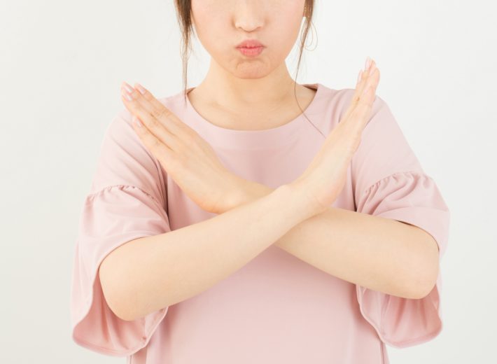 女性が胸の前で手をクロスさせ、バツマークを作っている画像