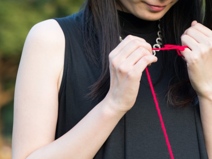 赤い糸で小指を結ばれている女性
