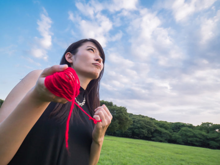 切れてしまった赤い糸を束ねている女性
