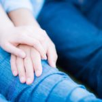 膝の上で手を重ね合っている男女