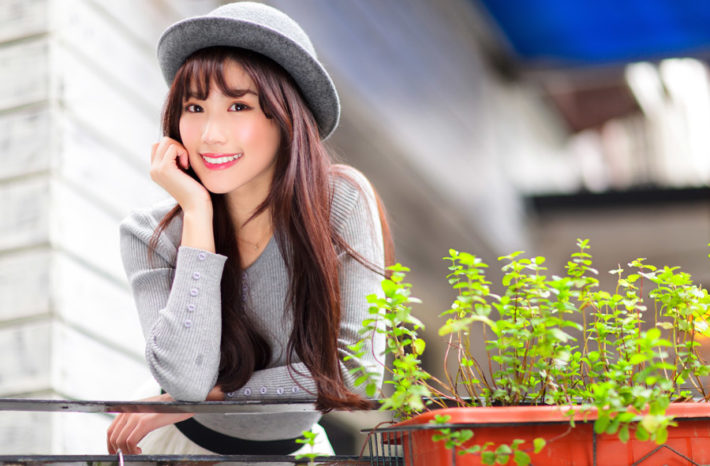 頬杖をついて微笑んでいる帽子をかぶった女性