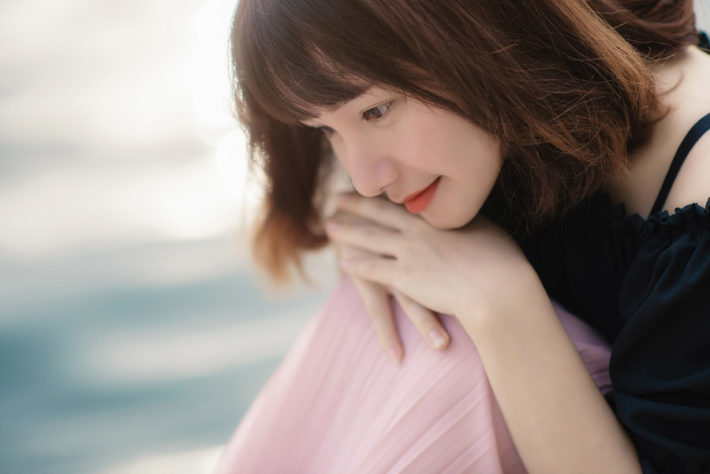 抱えた膝に頬を乗せて座っている女性