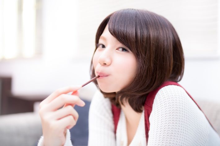 お菓子をくわえている女性