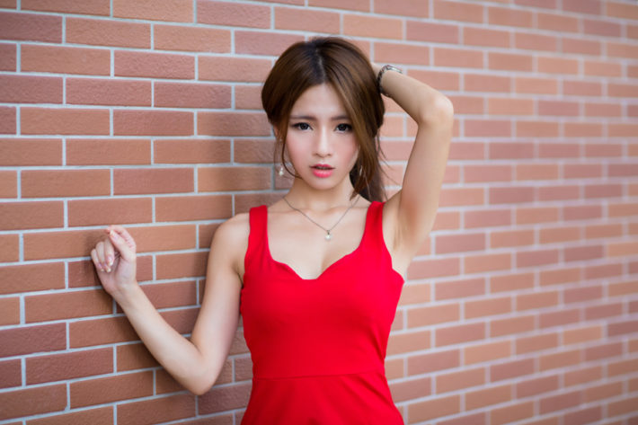 髪をかきあげている赤いドレスの女性