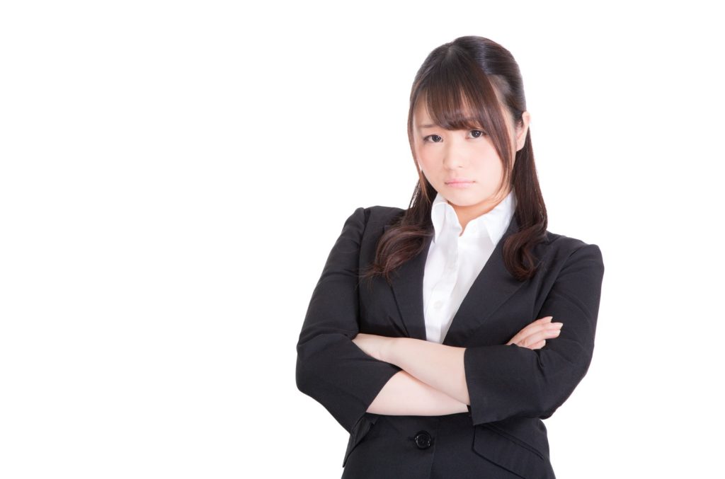 腕を組んでいるスーツ姿の女性