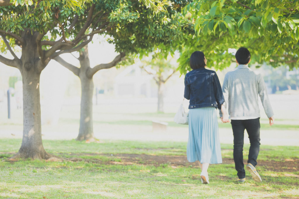 寄り添い合って公園を歩いている男女の後ろ姿