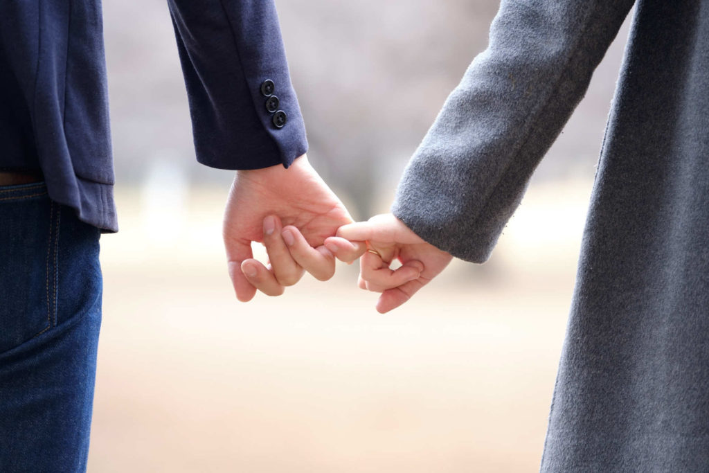 小指と小指を繋いで歩く男女