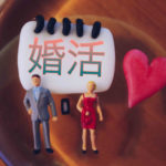 婚活と書かれたホワイトボードの前に置かれたミニチュアの男女
