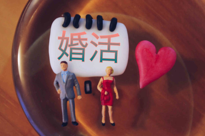 婚活と書かれたホワイトボードの前に置かれたミニチュアの男女