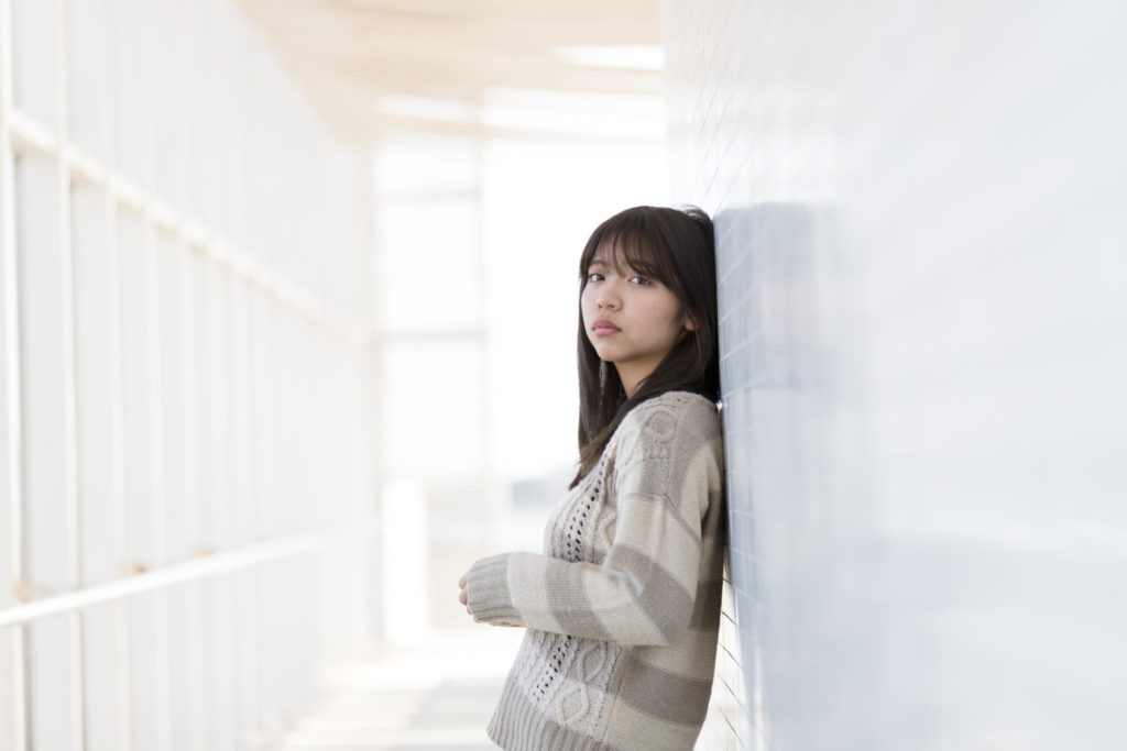 壁に寄りかかっている大学生の女の子