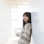 壁に寄りかかっている大学生の女の子