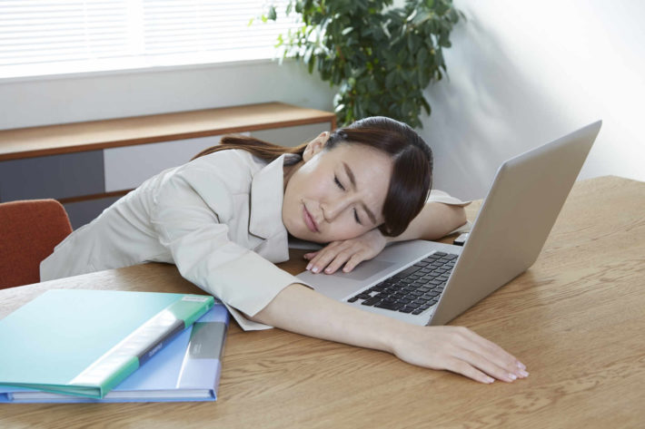 ターブルにうつ伏せて疲れた様子の女性