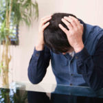 頭を抱えてうなだれている男性