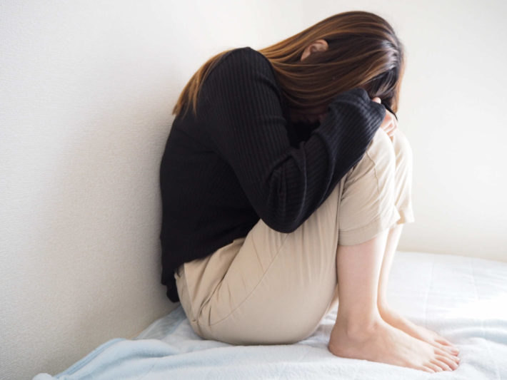 ベッドでうずくまり、疲れている様子の女性