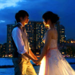夜の海辺で結婚式を挙げ見つめ合っている男女