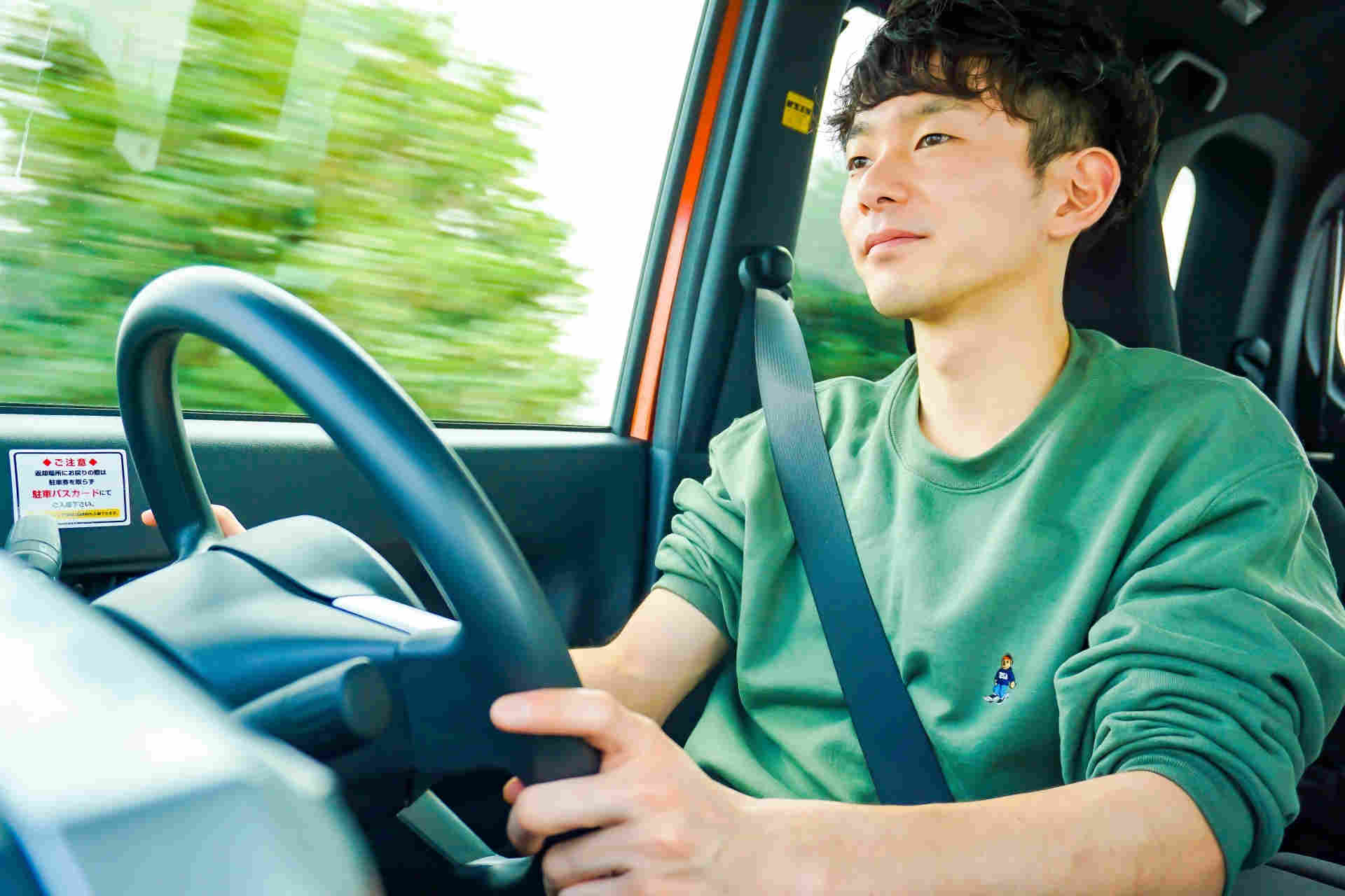 車を運転する緑のセーターを着た平凡そうな男性
