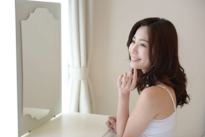 鏡を見て微笑んでいる女性