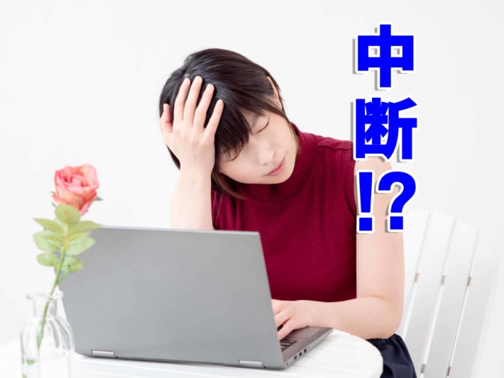 「中断！？」と書かれたテキストと、ノートPCの前で頭を抱える女性