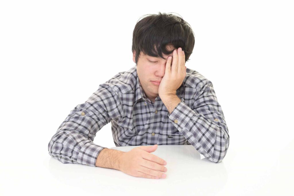 顔に手をあてて辛そうな表情をしている男性