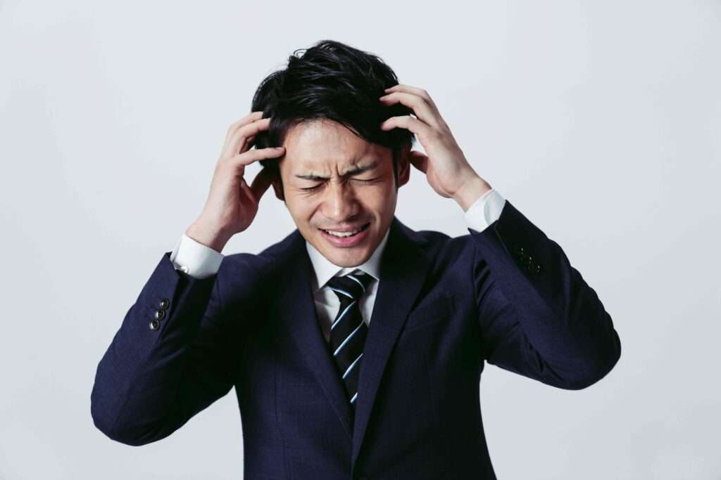 頭を抱えて悩んでいるスーツ姿の男性